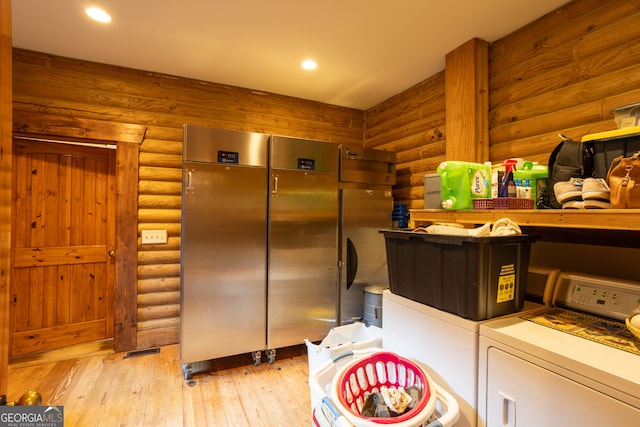 laundry room with light wood-type flooring, rustic walls, and washing machine and clothes dryer