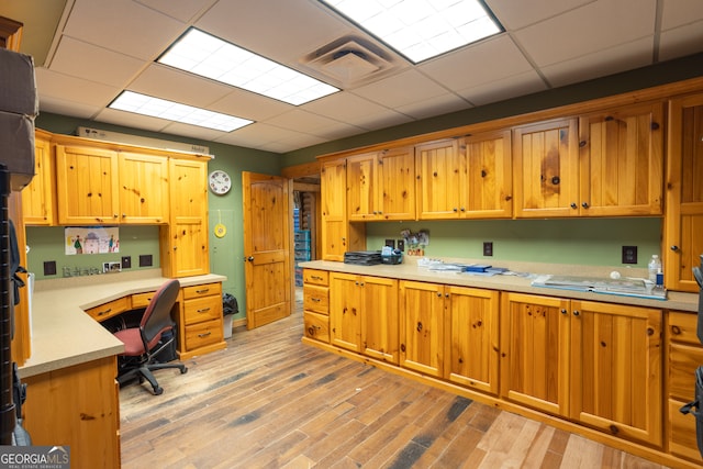 kitchen with light hardwood / wood-style flooring, built in desk, and a drop ceiling