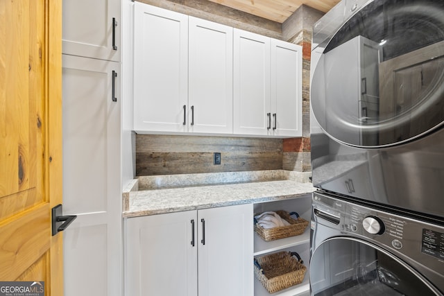 laundry area with cabinets and stacked washer and clothes dryer