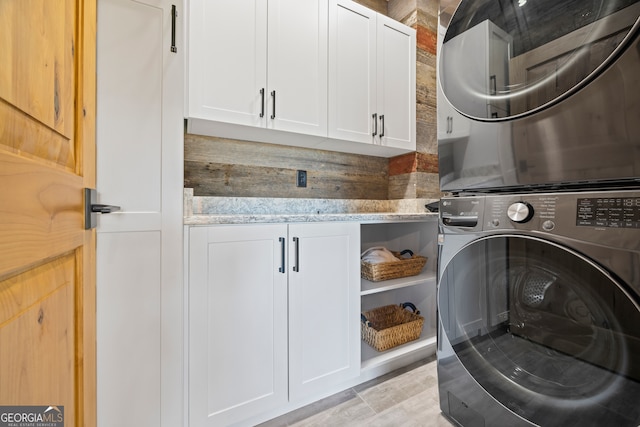 clothes washing area featuring cabinets and stacked washer and dryer