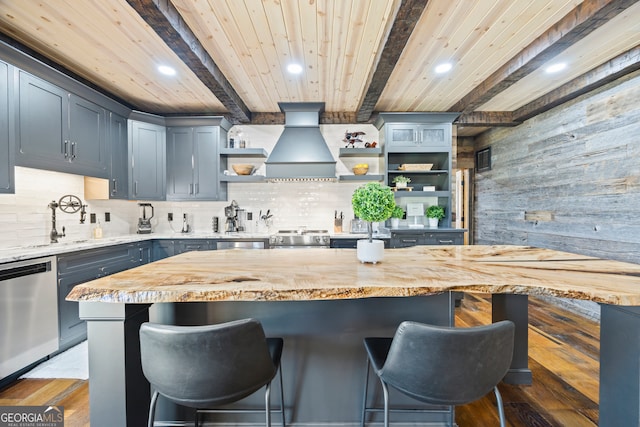 kitchen featuring dark wood-type flooring, stainless steel appliances, wood counters, beamed ceiling, and a breakfast bar area