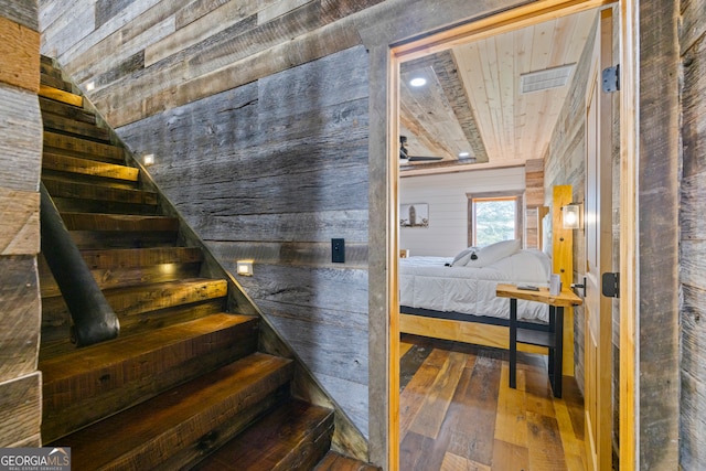 staircase featuring hardwood / wood-style floors, wood ceiling, and wooden walls