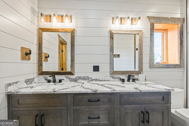 bathroom with wood walls, vanity, and toilet