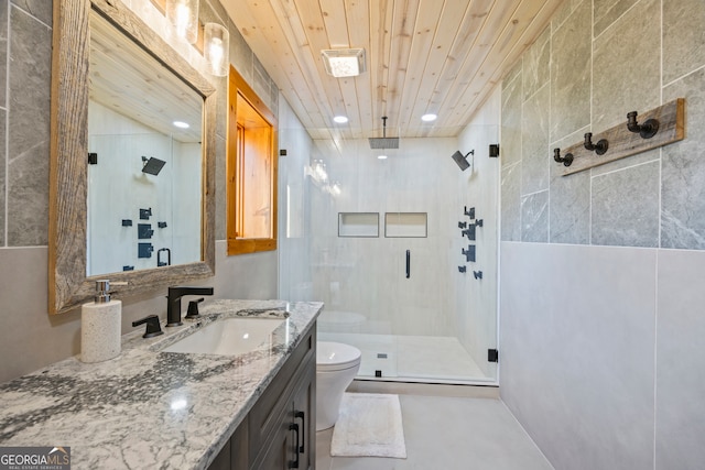 bathroom with vanity, toilet, tile walls, and a shower with shower door