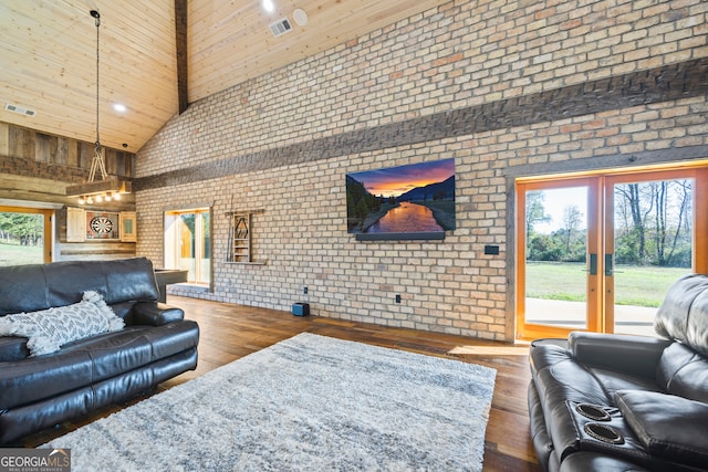 living room featuring hardwood / wood-style floors, high vaulted ceiling, a healthy amount of sunlight, and brick wall