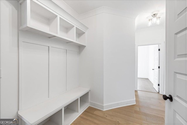 mudroom with light wood-style flooring, baseboards, and crown molding