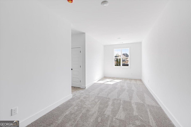 unfurnished room with light colored carpet and baseboards