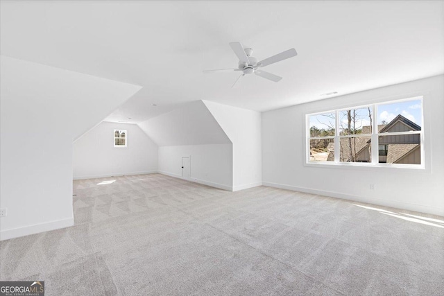 additional living space with light carpet, ceiling fan, baseboards, and vaulted ceiling