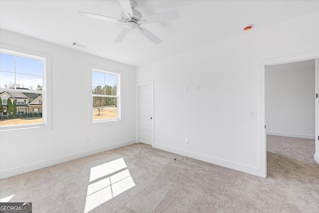 unfurnished room with baseboards, ceiling fan, visible vents, and light colored carpet