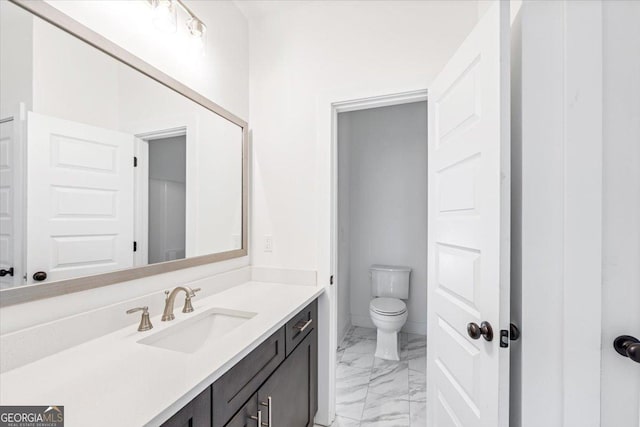 bathroom with marble finish floor, vanity, and toilet