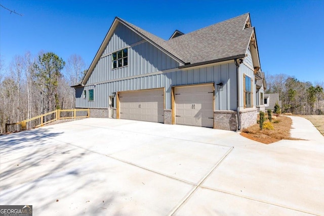 view of home's exterior with a garage, roof with shingles, board and batten siding, and driveway