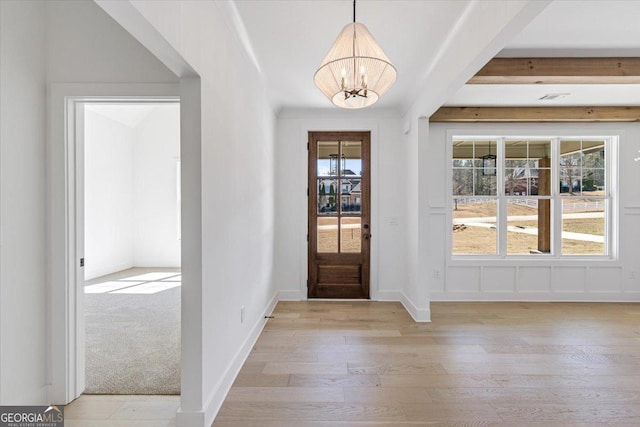 entryway with light wood-style floors, beam ceiling, baseboards, and a notable chandelier