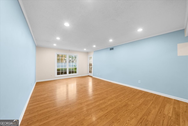 empty room featuring crown molding and light hardwood / wood-style flooring