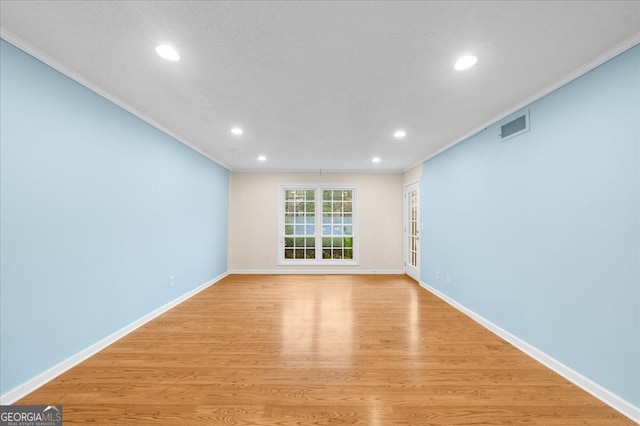 spare room featuring light hardwood / wood-style floors and ornamental molding