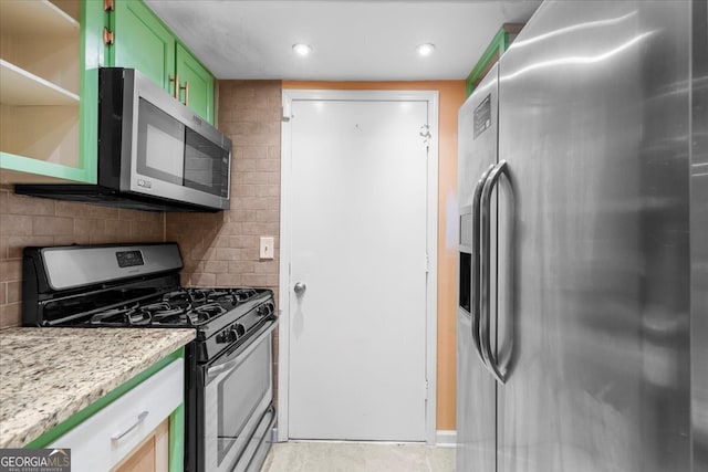 kitchen featuring backsplash, green cabinets, light stone countertops, and stainless steel appliances