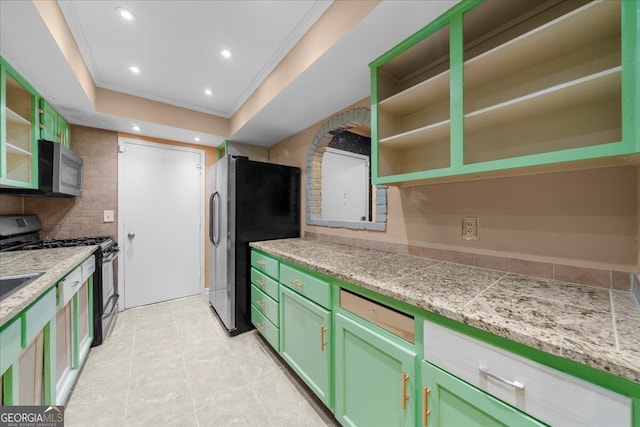 kitchen featuring crown molding, stainless steel appliances, tasteful backsplash, and green cabinetry