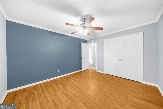 unfurnished bedroom with ceiling fan, a closet, light hardwood / wood-style floors, and ornamental molding