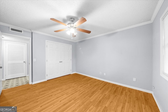 unfurnished bedroom with hardwood / wood-style floors, ceiling fan, ornamental molding, and a textured ceiling