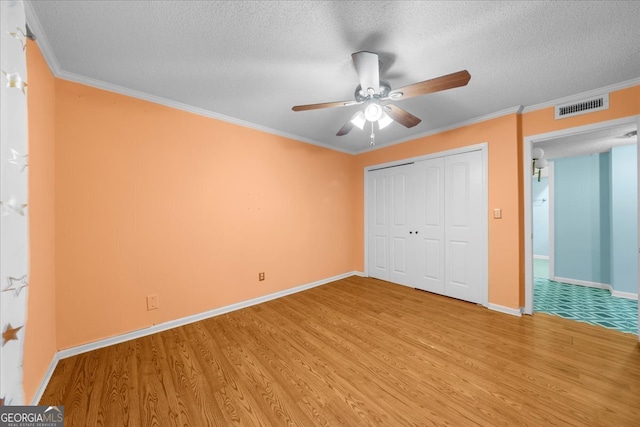 unfurnished bedroom featuring ceiling fan, crown molding, a textured ceiling, a closet, and hardwood / wood-style flooring