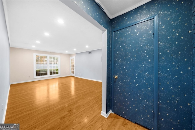 unfurnished living room with wood-type flooring and crown molding