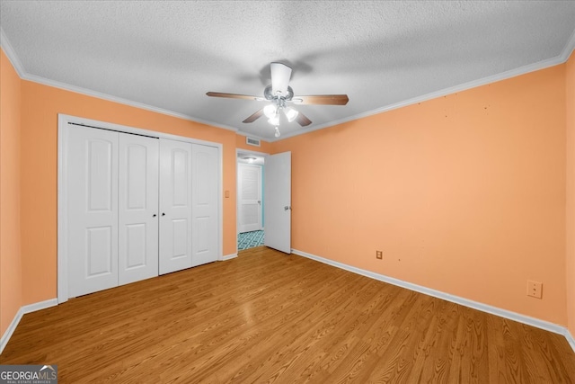 unfurnished bedroom featuring wood-type flooring, a textured ceiling, ceiling fan, and crown molding