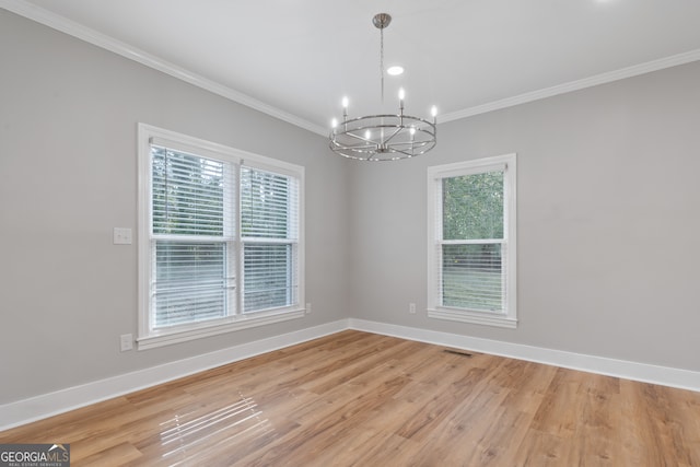 unfurnished room featuring a wealth of natural light, crown molding, wood-type flooring, and a notable chandelier