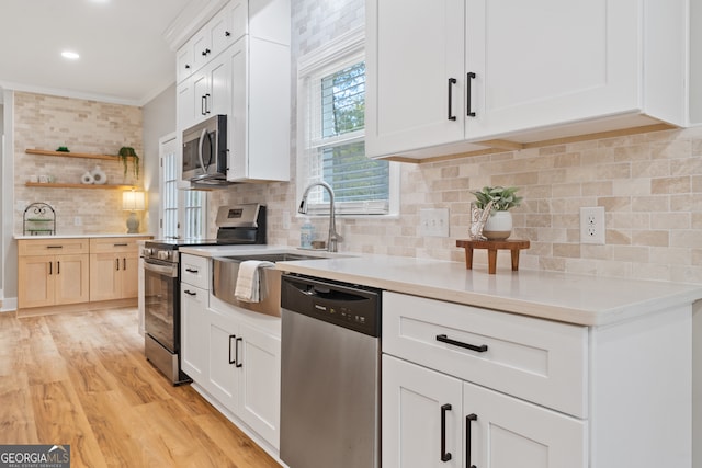 kitchen featuring tasteful backsplash, light hardwood / wood-style flooring, crown molding, white cabinets, and appliances with stainless steel finishes