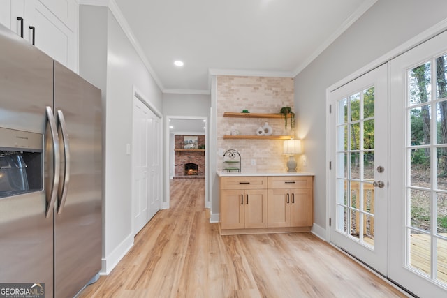 kitchen with light brown cabinetry, light wood-type flooring, ornamental molding, a fireplace, and stainless steel fridge with ice dispenser