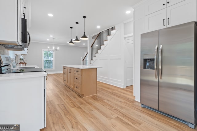 kitchen featuring stainless steel appliances, crown molding, pendant lighting, white cabinetry, and a kitchen island