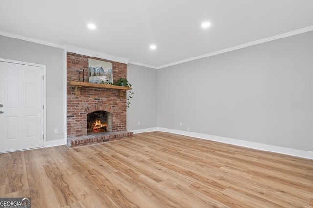 unfurnished living room featuring a brick fireplace, light hardwood / wood-style flooring, and crown molding