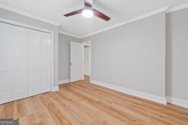 unfurnished bedroom with ceiling fan, light wood-type flooring, crown molding, and a closet