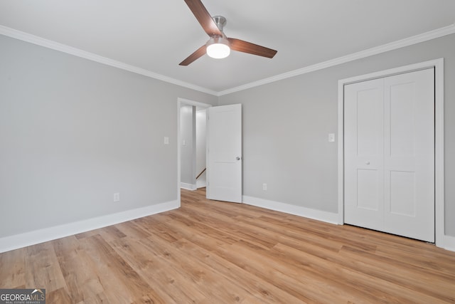 unfurnished bedroom featuring ceiling fan, light wood-type flooring, crown molding, and a closet