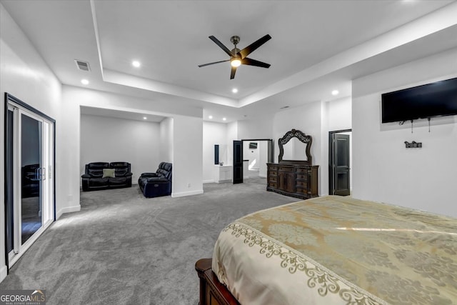 carpeted bedroom featuring a tray ceiling and ceiling fan