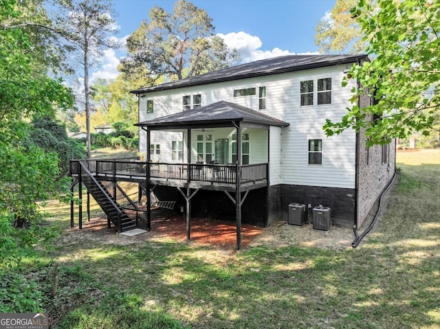 back of house with central AC unit, a deck, and a lawn