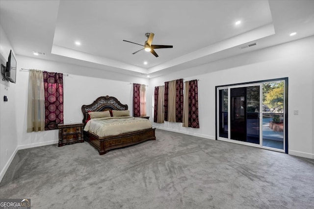 bedroom with carpet floors, access to outside, ceiling fan, and a tray ceiling