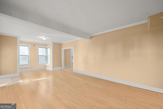 spare room featuring crown molding and light wood-type flooring