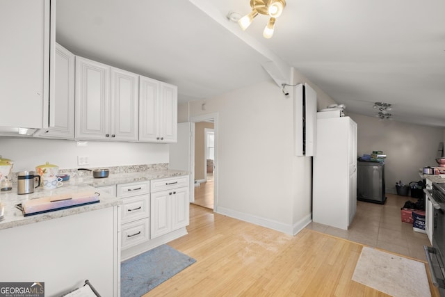 kitchen with white cabinets, white refrigerator, light hardwood / wood-style floors, and light stone counters