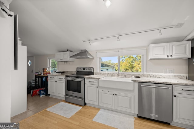 kitchen featuring white cabinets, wall chimney range hood, sink, and appliances with stainless steel finishes