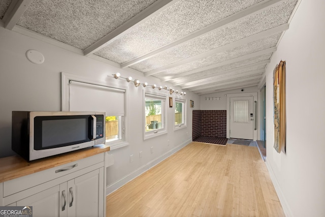 living room featuring vaulted ceiling with beams and light hardwood / wood-style floors