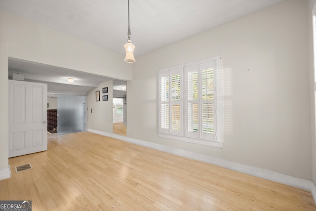 empty room featuring vaulted ceiling and light hardwood / wood-style flooring