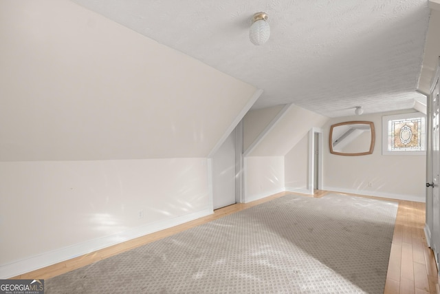 bonus room featuring wood-type flooring, a textured ceiling, and lofted ceiling