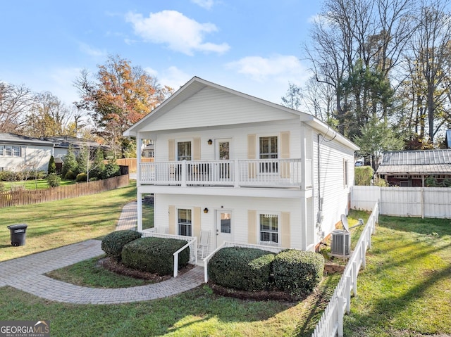 view of front of home featuring cooling unit, a balcony, a front lawn, and a porch