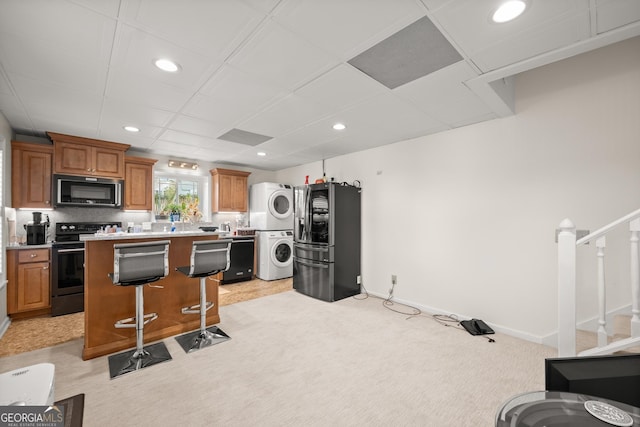 kitchen with light carpet, stacked washer and clothes dryer, a kitchen breakfast bar, tasteful backsplash, and stainless steel appliances