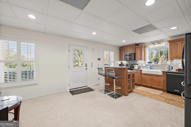 kitchen with a kitchen breakfast bar, sink, appliances with stainless steel finishes, a kitchen island, and light colored carpet