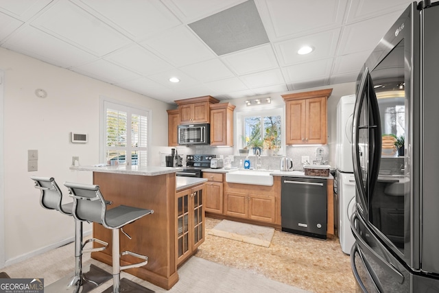 kitchen with sink, stainless steel appliances, tasteful backsplash, a breakfast bar area, and a kitchen island