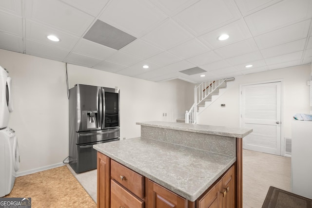 kitchen with stacked washer / drying machine, a center island, light colored carpet, and stainless steel fridge with ice dispenser