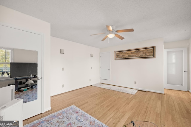 living room with ceiling fan, light hardwood / wood-style floors, and a textured ceiling