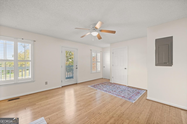 interior space with a textured ceiling, electric panel, light hardwood / wood-style flooring, and ceiling fan