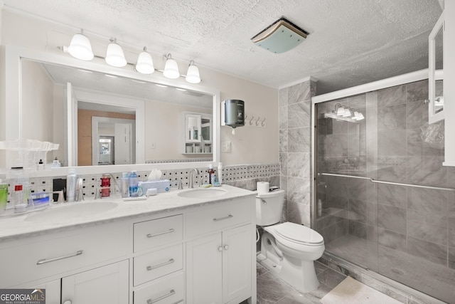 bathroom with a textured ceiling, vanity, tile walls, toilet, and a shower with shower door