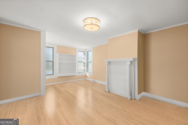 unfurnished living room with hardwood / wood-style flooring, built in shelves, and ornamental molding